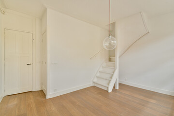 A bright, minimalist interior showcasing a staircase, wooden flooring, and a pendant light,...