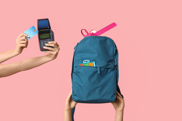 Female hands with backpack, different school supplies, credit card and payment terminal on pink...