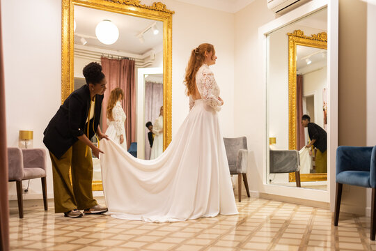 Bride Tries On Wedding Dress With Assistance In Boutique