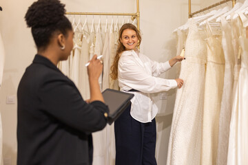 Bride selects wedding dress under guidance in luxury boutique