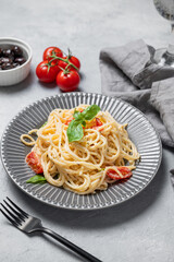 Generated imageCreamy spaghetti with cherry tomatoes, parmesan cheese and basil on a plate on a light background with glass of water and olives. Italian or Mediterranean cuisine concept. Top view.