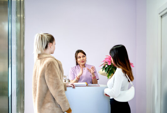 Beauty Salon Receptionist Assisting Clients in Modern Lobby