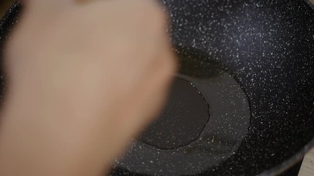 Cooking fried eggs sunny side up with a sizzling oil in frying pan.
