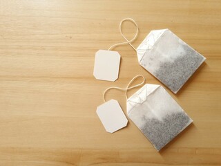 Two tea bags with empty tags on wooden background