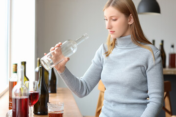 Young woman drinking alcohol at home. Concept of alcoholism