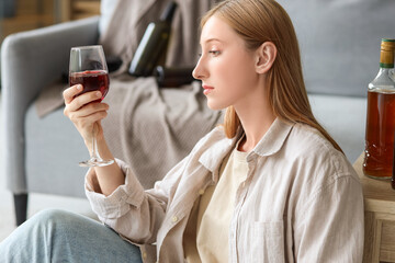 Young woman drinking alcohol at home. Concept of alcoholism