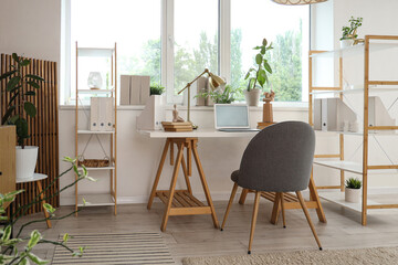 Interior of modern office with workplace, shelf units and window