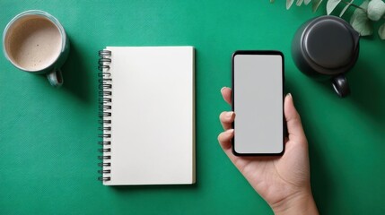 Obraz premium Woman's hand holding smartphone with blank screen, office workspace with green table and coffee.