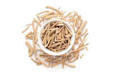 A bowl of Organic Ashwagandha (Withania somnifera) roots, placed over a heap of whole ashwagandha roots. Isolated on a white background.