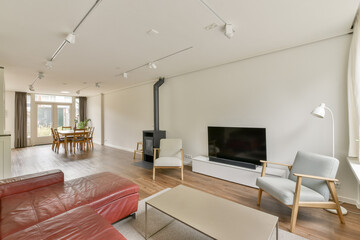 This contemporary living room features a stylish sofa, a sleek television, and warm natural light streaming through large windows, creating a welcoming space.