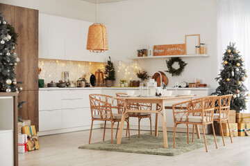 Interior of kitchen with Christmas trees, dining table and glowing lights © Pixel-Shot