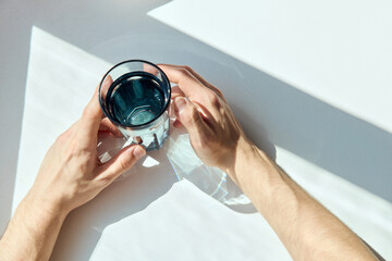 men's hands with a glass of water in the morning sun