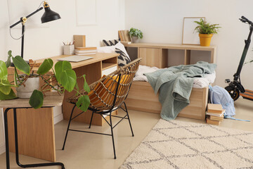 Interior of light children's room with bed, study table and kick scooter