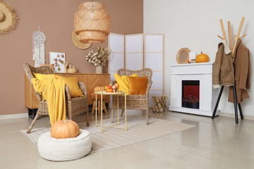 Interior of stylish living room with wicker armchairs, fireplace and autumn decor