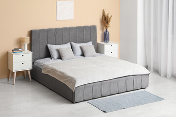 Beautiful bedroom with comfortable bed, bedside tables and vase of pampas grass