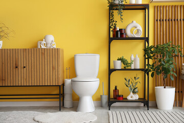 Interior of restroom with toilet bowl, commode and shelf unit