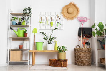 Fototapeta premium Workplace with pegboard, gardening tools and plants near white wall in barn