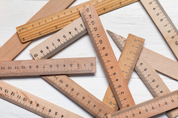Many rulers on light wooden background, closeup