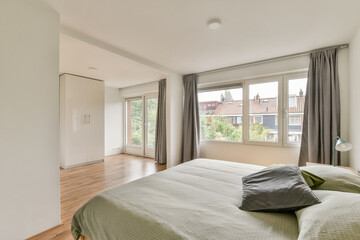 Bright and airy bedroom featuring large windows, neutral tones, and minimalist decor. A calm and inviting space with wood flooring and soft textiles.