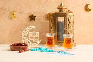 Dates, prayer beads and glass cups of tea on white table against beige background. Ramadan celebration