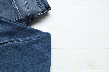 Stylish jeans on white wooden background