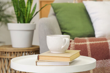 Cup of tea with books on table in living room, closeup