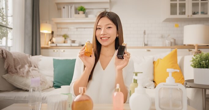 POV webcam view of Asian woman beauty influencer, content creator smiling while presenting skincare products to camera at home. vlog self care product review. Gen Z lifestyle social media trends.