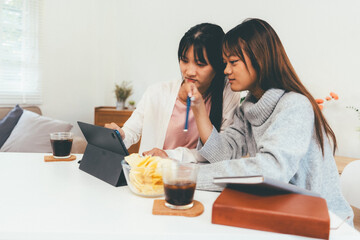 Female higher education student using laptop and studying book in home, Online learning.