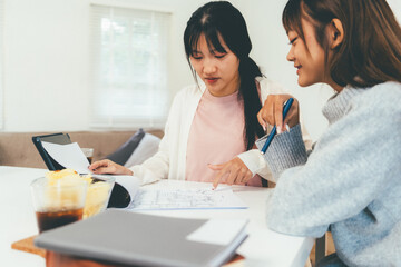 Obraz premium Female higher education student using laptop and studying book in home, Online learning.