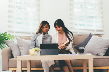 Female higher education student using laptop and studying book in home, Online learning.