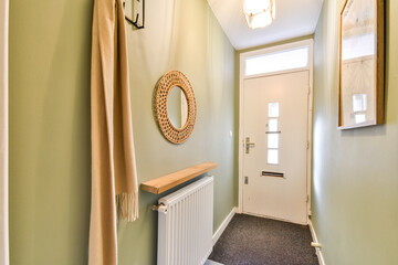 An elegant entrance hall featuring a minimalist design with soft green walls, a round mirror, and a...
