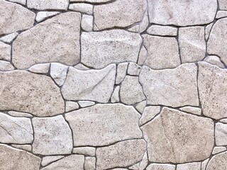 Rough uneven strong stone wall surface texture isolated on horizontal background.