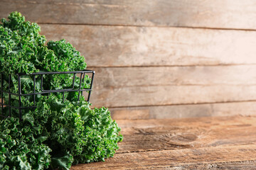 Basket with fresh leaves of kale cabbage on wooden background