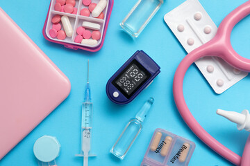 Composition with pulse oximeter, stethoscope and medicines on blue background, closeup