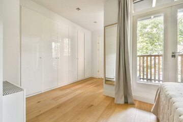 A spacious, well-lit modern interior featuring sleek white cabinetry and elegant wooden floors, blending comfort with contemporary aesthetics.