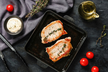 Frying pan with roasted steaks on dark background