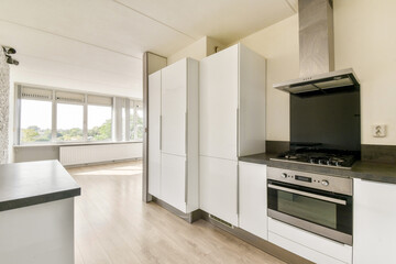 A stylish modern kitchen featuring sleek cabinets, stainless steel appliances, and ample natural light from large windows, creating an inviting cooking space.