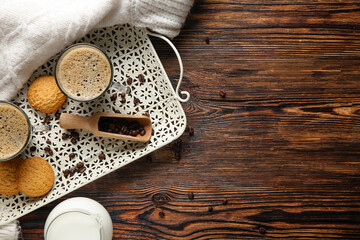 Glass cups of hot coffee with sweet cookies and jug of fresh milk on wooden background