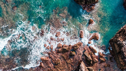 Aerial view of ocean waves crashing on rocky cliffs. stunning summer nature background for travel projects.