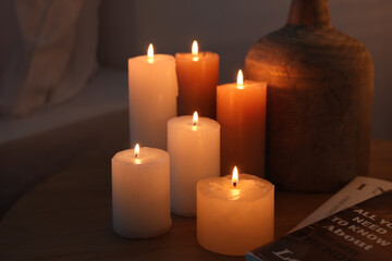 Burning candles with vase on table in bedroom at night, closeup