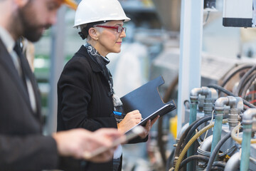 Quality inspectors team and workers at factory using machines