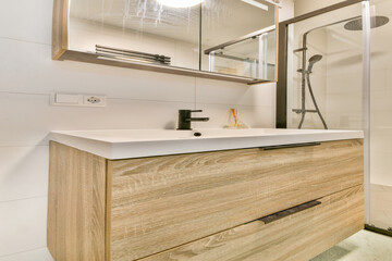 A stylish modern bathroom featuring a wooden vanity, sleek sink, and a frameless glass shower. The clean lines and minimalistic design create a serene atmosphere.