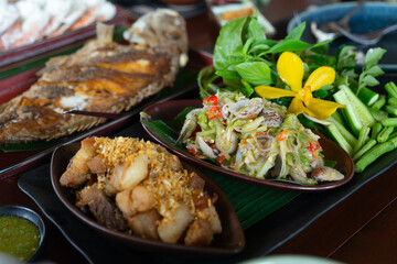 Southern-style Thai cuisine and seafood dishes are beautifully arranged on the table, looking...