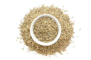 A bowl of Organic Fennel Seeds (Foeniculum vulgare) Badi saunf, placed over a heap of whole  Fennel Seeds. Isolated on a white background.
