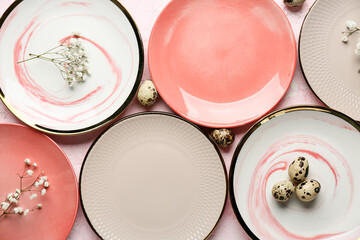 Different clean plates with quail eggs and beautiful gypsophila flowers on light pink background....