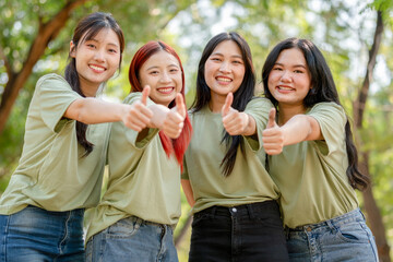 Group of cheerful young volunteer woman showing thumbs up in park