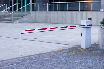 Lowered automatic parking barrier gate at office building entrance on paved driveway surface