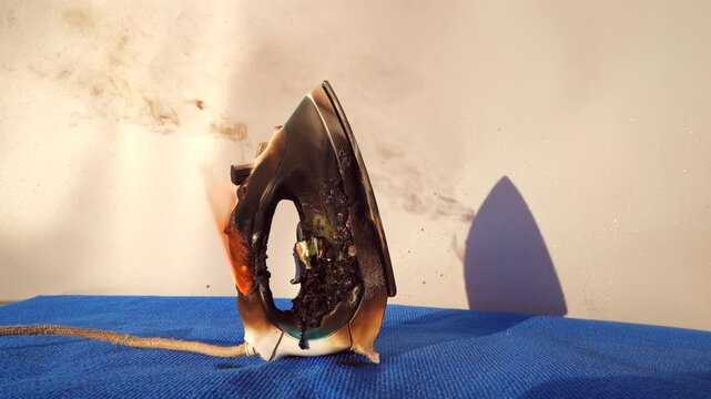 Electrical Short Circuit. Fire socket of electricity plug switch. Burning electric iron. Electric iron in fire. Short circuit in Overloaded. Smoke Burned electric iron. Burning household appliance.