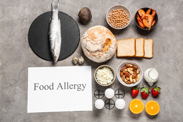 Different products and paper with text FOOD ALLERGY on grunge background