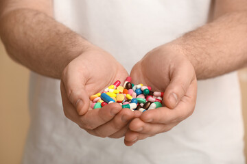Male hands with different pills on beige background, closeup